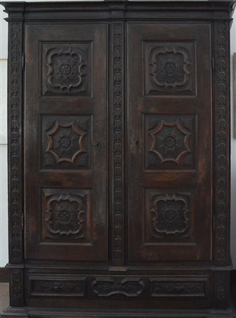 Armadio in noce a patina scura a due ante e un cassetto intagliati a...