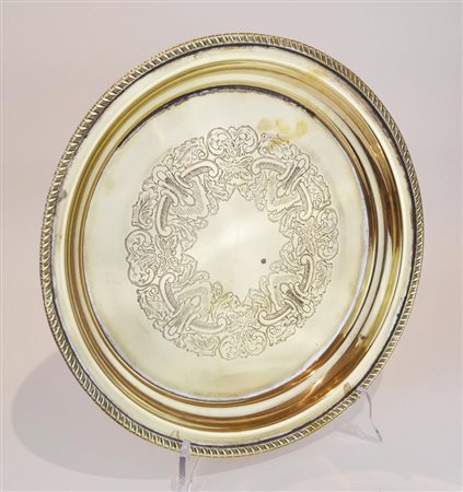 VASSOIO IN METALLO ARGENTATO DORATO di forma rotonda, sbalzato e cesellato,...