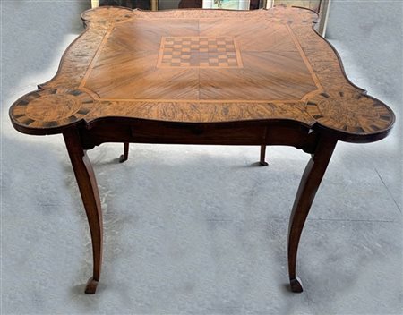 Tavolo da gioco con piano di forma mossa lastronato e filettato in legni vari,