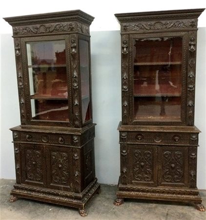 Coppia di mobili a due corpi in legno intagliato a volute, fiori e mascheroni.