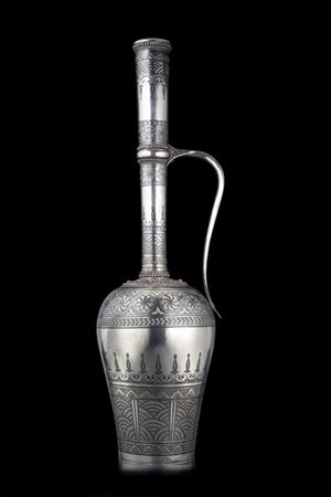 Versatoio in argento niellato e cesellato a motivi geometrici. Ansa a voluta, i