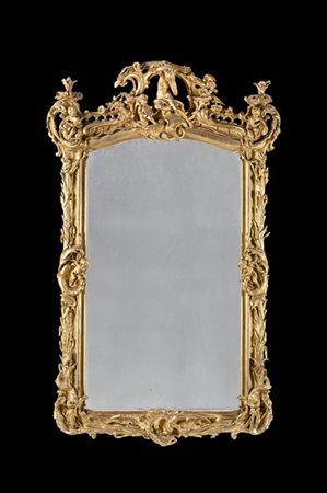 Grande specchiera in legno scolpito e dorato e pastiglia. Cimasa intagliata con