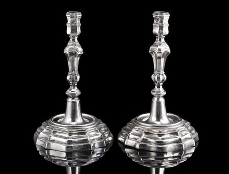 Coppia di candelieri in argento sbalzato con basi polilobate e fusti scanalati.