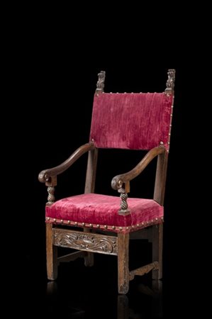 Seggiolone in noce intagliato con braccioli terminanti a ricciolo, finali e fas