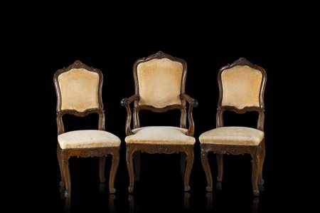 Lotto composto da una poltrona e due sedie di forma mossa in noce intagliato a