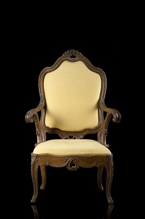 Poltrona in noce intagliato di forma mossa, schienale sormontato da conchiglia