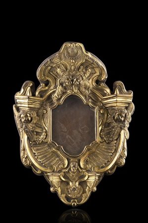 Cartagloria di forma mossa in bronzo decorato a volute e cesellato a teste di c