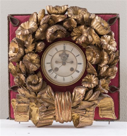 Orologio inserito in ghirlanda in legno intagliato e dorato. Cm 35x32x10.