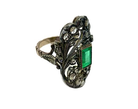 Anello in oro e argento con radice di smeraldo rettangolare in centro e rosette di diamanti. Mis. cm 2,50