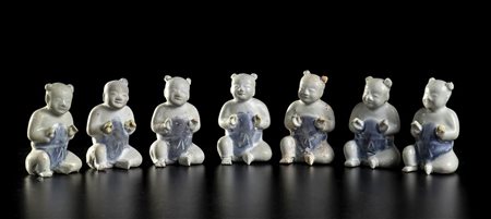 SETTE BAMBINI SEDUTI IN PORCELLANA INVETRIATA<br>Cina, dinastia Qing, 1750 circa