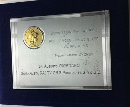 <br>Placca da tavolo 1985 A Donna Maria Pia Fanfani "Per l'amore per lo stato ed al prossimo" da Augusto Giordano RAI TV GR2 (misura della placca 119x155 mm). Base in velluto blu.