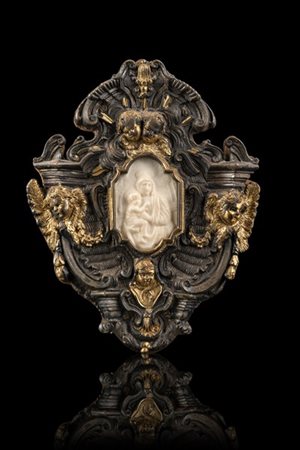 Cornice in argento con teste di cherubini e dettagli dorati. Al centro placca i