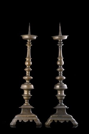 Coppia di portaceri in bronzo a rocchetto con base tripode incisa a ostensorio.