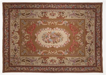  MANIFATTURA FRANCESE DEL XX SECOLO - Tappeto a piccolo punto in stile Aubusson, medaglione centrale su tono crema in campo bruno, decori vegetali e floreali.