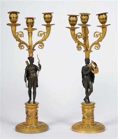 Coppia di candelabri a tre fiamme in bronzo cesellato, dorato e patinato....