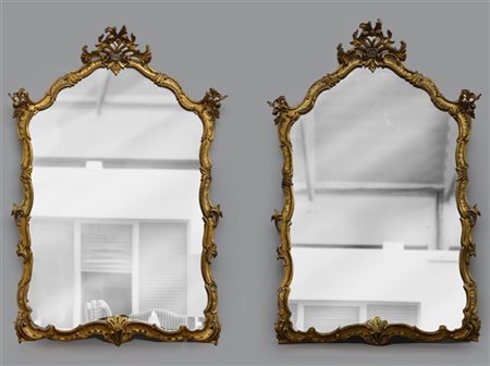 Coppia di specchiere di forma mossa in legno intagliato e dorato a volute fogli