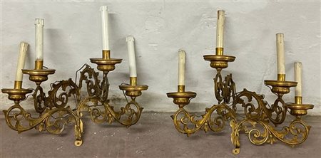 Coppia di appliques a quattro fiamme in metallo dorato, decorate a volute a mot
