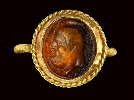 A roman orange glass paste intaglio, mounted on an ancient gold ring. Head of Hercules. 