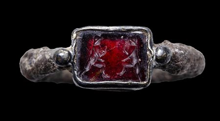 A silver late roman signet ring with a garnet intaglio. Warriors.
