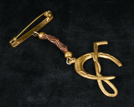 SPILLA in ottone dorato con pendente a ferro di cavallo e frustino Italia,...