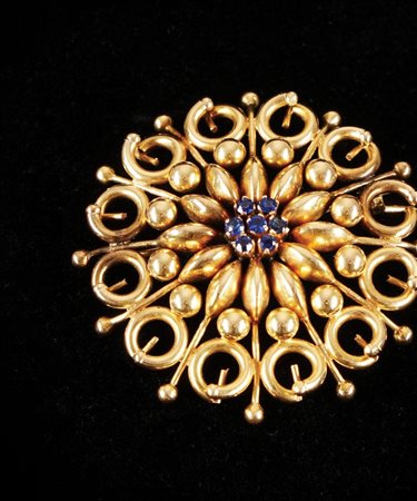Spilla in oro giallo 18kt. cesellata a corolla con piccoli zaffiri, d. cm....