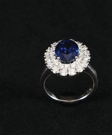 Anello in oro bianco 18kt. con zaffiro centrale contornato da diamanti; lo...