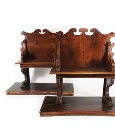 Due panche di noce con dossello dal profilo intagliato a volute così come i...