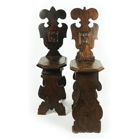 Coppia di sgabelli di noce con profilo del dossello intagliato a volute,...