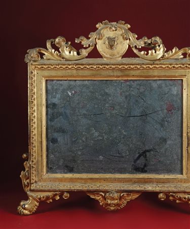 Cartagloria in legno dorato con cimasa scolpita a foglie; due pieducci...