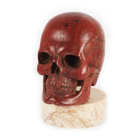 Scultura in rosso antico raffigurante un teschio; base circolare in marmo...