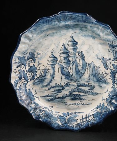 Piatto in maiolica bianca e blu dipinto a raffigurare un paesaggio con...