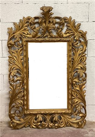 Specchiera di forma sagomata con cornice in legno dorato, traforato e scolpito