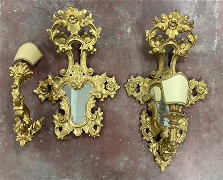 Coppia di appliques di forma sagomata ad una fiamma in legno dorato e intagliat