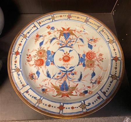 Un grande piatto in porcellana a decoro Imari con ghiera in metallo
Sec. XIX (d