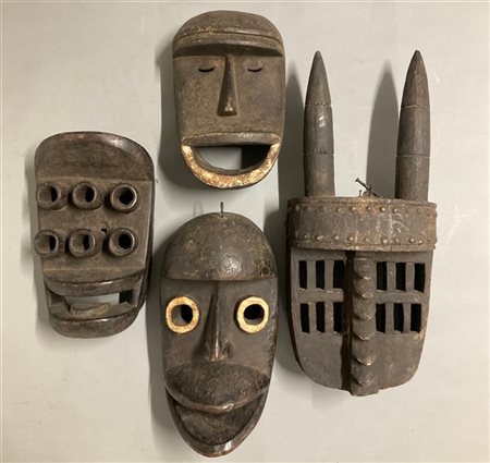 Arte africana, lotto di quattro maschere in legno scolpito, pigmenti e borchie