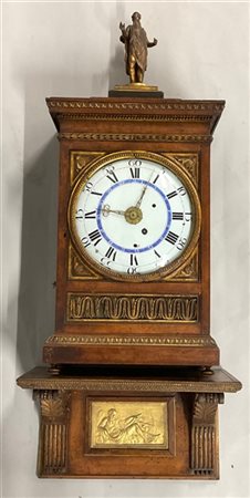 Pendola con cassa in legno intagliato sormontata da figura religiosa in metallo