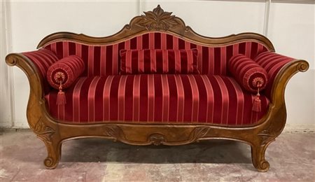 Divano in noce di forma sagomata con schienale e fascia intagliata a motivi veg