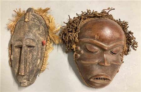 Arte africana, lotto di due maschere di etnie differenti in legno scolpito e fi