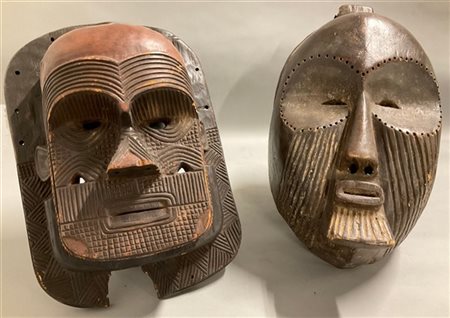 Arte africana, lotto di due grandi maschere in legno scolpito con tracce di pig