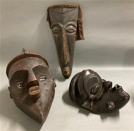 Arte africana, lotto di tre maschere in legno scolpito, tracce di pigmenti e ju