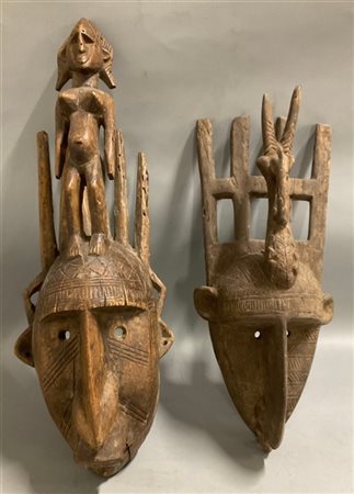 Arte africana, lotto di due maschere in legno scolpito con caschi sormontati da