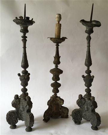 Lotto composto da tre antiche torciere tripodi in metallo sbalzato con decoro a