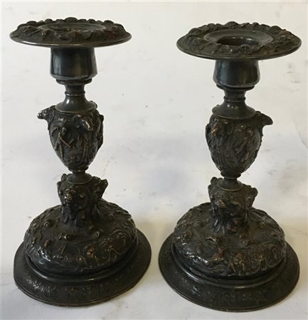 Coppia di candelieri in metallo sbalzato con decoro a figure mitologiche e test