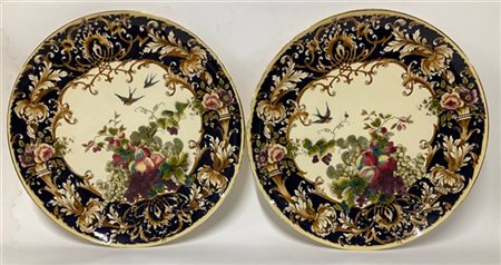 Coppia di piatti da parete in ceramica decorati a volute, motivi vegetali, frut