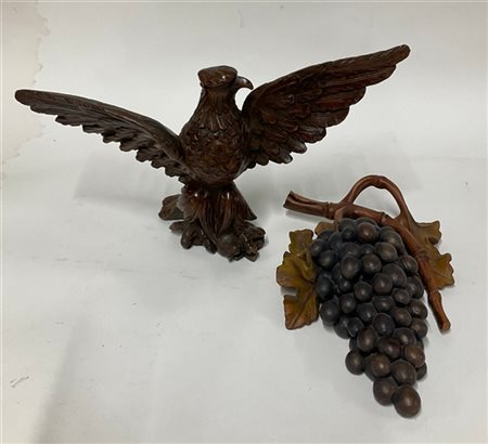 Lotto di due sculture in legno raffiguranti un grappolo d'uva ed un'aquila ad a