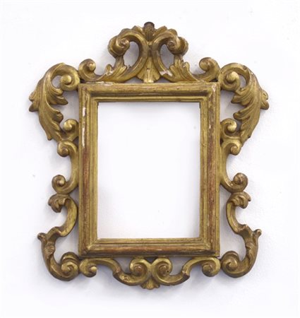 Cornice di forma sagomata in legno intagliato e dorato a volute fogliate e ricc