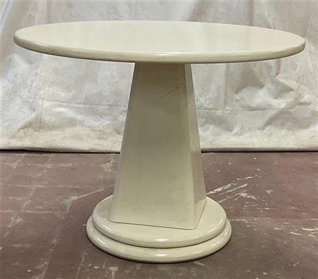 Tavolo in legno verniciato bianco con base troncopiramidale e piano circolare.