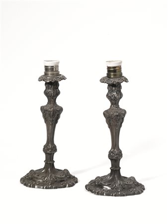 Coppia di candelieri, in argento sbalzato e cesellato a volute, fusto a...