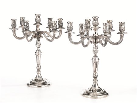 Coppia di candelabri, in argento fusto a balaustro stampato a volute di...