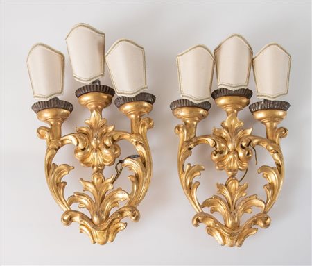 Coppia di appliques a tre fiamme dorate in legno intagliato e dorato. XIX...